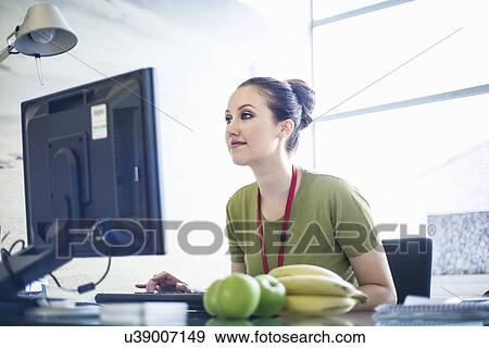Stock Photo - Young woman using computer in office. Fotosearch