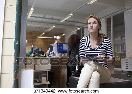 Stock Image - Young woman using digital tablet in office. Fotosearch