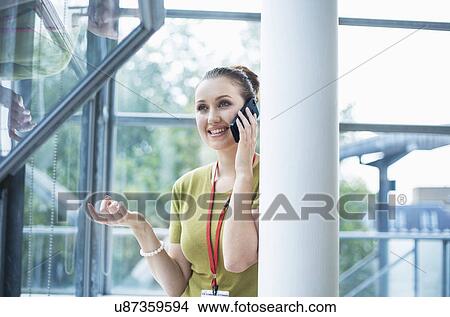 Picture - Young woman using smartphone beside pillar. Fotosearch