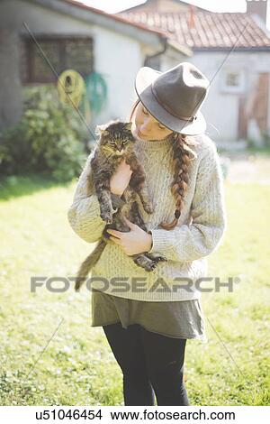 Picture - "Young woman wearing hat, holding cat". Fotosearch