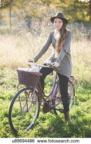 Young woman wearing hat on bicycle View Large Photo Image Stock Photograph - Young woman wearing hat on bicycle. Fotosearch