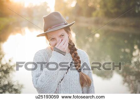 Young woman wearing hat with hand covering mouth View Large Photo Image Stock Photo - Young woman wearing hat with hand covering mouth. Fotosearch
