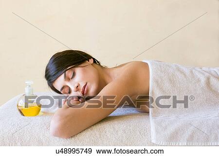 Young woman with eyes closed lying on treatment couch at spa View Large Photo Image Stock Photo - Young woman with eyes closed lying on treatment couch at spa. Fotosearch