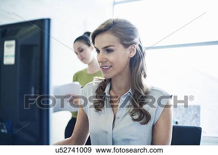 Stock Photo - Young women working in office. Fotosearch