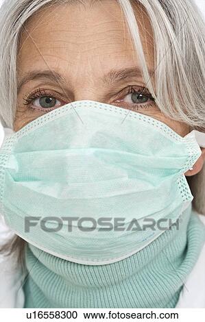 Stock Image - Mature female doctor wearing surgical mas. Fotosearch