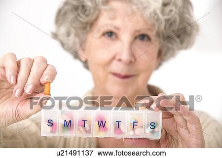 Stock Photo - Woman holding pill and pill container. Fotosearch