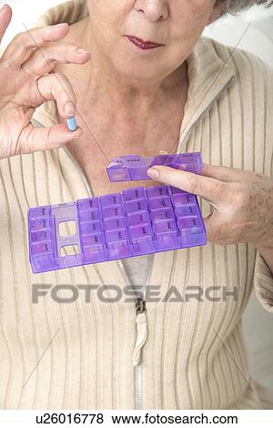 Stock Photo - Woman holding pill and pill container. Fotosearch