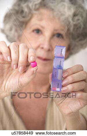 Woman holding pill and pill container View Large Photo Image Stock Photo - Woman holding pill and pill container. Fotosearch