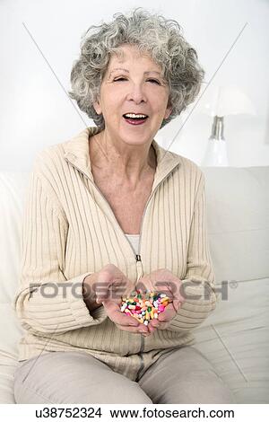 Picture - Woman holding pills. Fotosearch