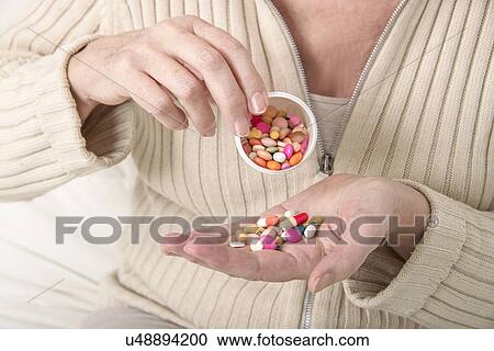 Stock Image - Woman holding pills. Fotosearch