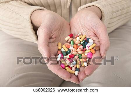Stock Photograph - Woman holding pills. Fotosearch