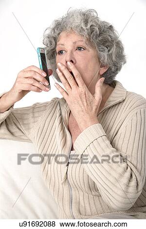 Stock Photo - Woman holding smartphone, covering mouth. Fotosearch