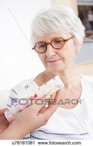 Stock Image - Woman looking at pill container. Fotosearch