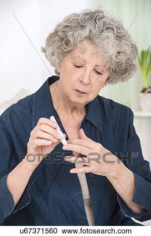 Stock Image - Woman using finger prick test. Fotosearch