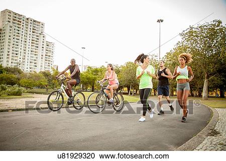 Adult friends doing training run and cycle in park View Large Photo Image Stock Image - Adult friends doing training run and cycle in park. Fotosearch