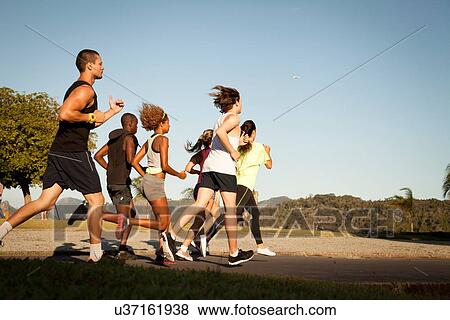 Stock Photo - Adult friends doing training run in park. Fotosearch