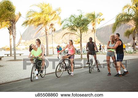 Stock Image - "Adult friends training in park on bicycles, Rio De Janeiro, Brazil". Fotosearch
