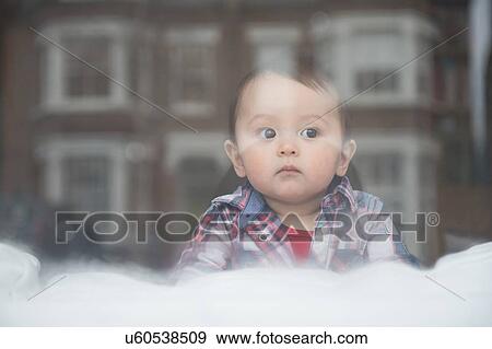 Stock Photo - "Baby boy looking out of window, view through window". Fotosearch