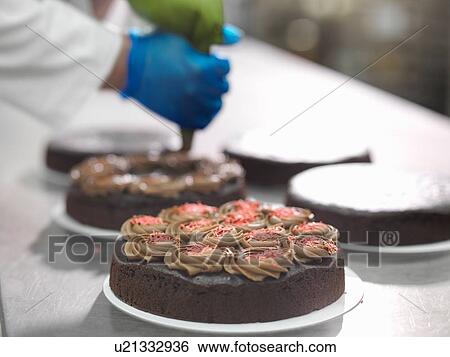 "Baker piping chocolate onto cakes in cake factory, close up" View Large Photo Image Stock Photograph - "Baker piping chocolate onto cakes in cake factory, close up". Fotosearch
