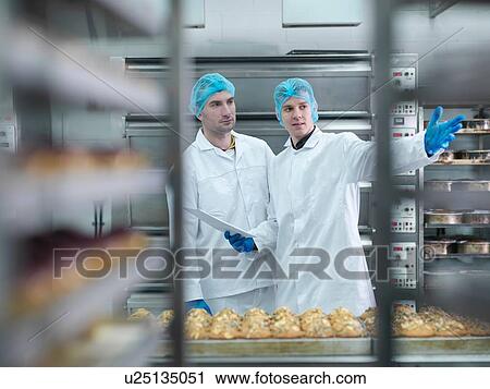 Stock Image - Bakers in meeting in cake factory. Fotosearch