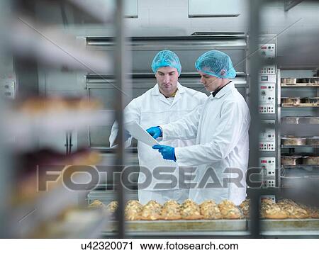 Stock Image - Bakers in meeting in cake factory. Fotosearch