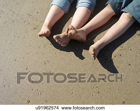 Picture - "Boy and sisters feet on sandy beach, close up". Fotosearch