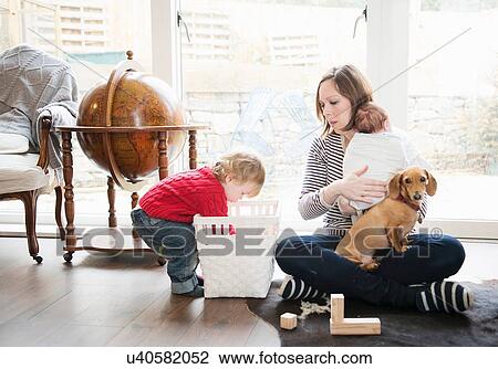 Stock Image - Boy playing at home with mother and baby sister. Fotosearch