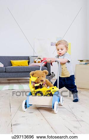 Boy pushing cart of toys at home View Large Photo Image Stock Photograph - Boy pushing cart of toys at home. Fotosearch