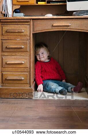 Boy sitting on floor under desk View Large Photo Image Stock Image - Boy sitting on floor under desk. Fotosearch