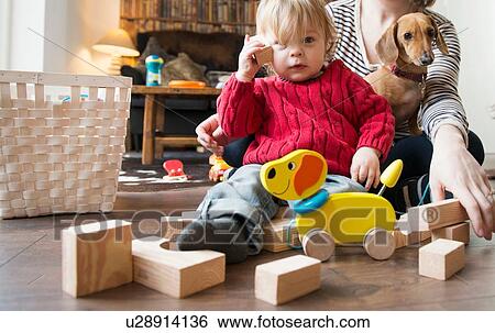 Boy sitting on floor with wooden toys View Large Photo Image Stock Photograph - Boy sitting on floor with wooden toys. Fotosearch