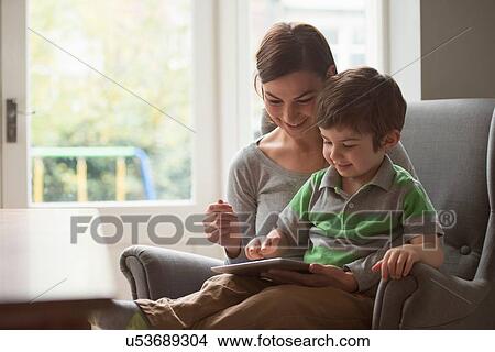 Boy sitting on mother's lap and using digital tablet View Large Photo Image Picture - Boy sitting on mother's lap and using digital tablet. Fotosearch