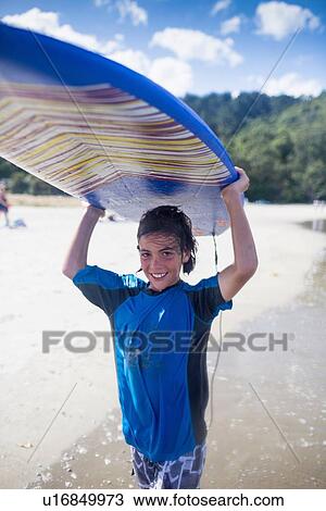 Boy surfer carrying surfboard View Large Photo Image Stock Image - Boy surfer carrying surfboard. Fotosearch