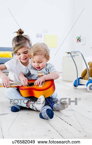 Brother and sister playing toy guitar at home View Large Photo Image Stock Photo - Brother and sister playing toy guitar at home. Fotosearch