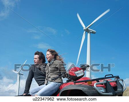 Stock Image - Brother and sister sitting on quadbike at windfarm. Fotosearch