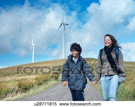Stock Photography - Brother and sister walking on path at windfarm. Fotosearch