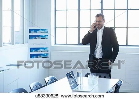 Stock Photography - Business man chatting on smartphone in conference room. Fotosearch