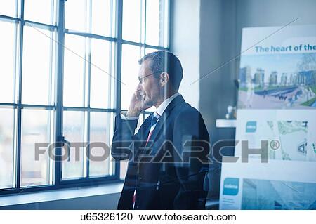 Business man chatting on smartphone whilst looking out of office window View Large Photo Image Stock Image - Business man chatting on smartphone whilst looking out of office window. Fotosearch