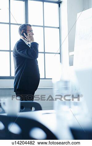 Business man in conference room chatting on smartphone View Large Photo Image Stock Image - Business man in conference room chatting on smartphone. Fotosearch