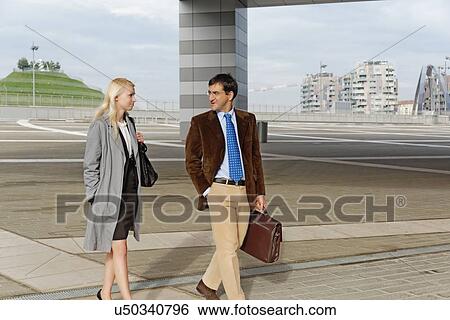 Stock Photograph - "Businessman and businesswoman, walking together, outdoors". Fotosearch