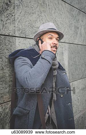 Businessman leaning against wall talking on smartphone View Large Photo Image Stock Photo - Businessman leaning against wall talking on smartphone. Fotosearch