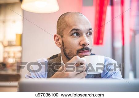 Stock Image - Businessman sitting in cafe drinking coffee. Fotosearch