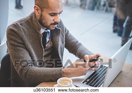 Businessman sitting in cafe texting on smartphone View Large Photo Image Stock Image - Businessman sitting in cafe texting on smartphone. Fotosearch
