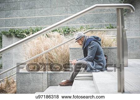 Businessman sitting on stairway texting on smartphone View Large Photo Image Stock Photo - Businessman sitting on stairway texting on smartphone. Fotosearch