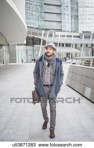 Stock Image - Businessman walking outside office buildings. Fotosearch