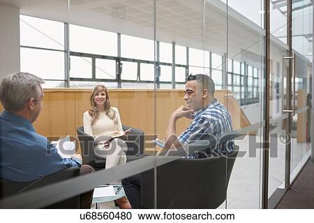 Stock Image - Businessmen and woman at team meeting in conference room. Fotosearch