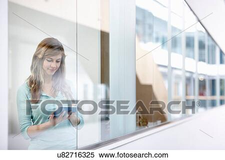 Businesswoman using digital tablet behind office window View Large Photo Image Stock Photography - Businesswoman using digital tablet behind office window. Fotosearch