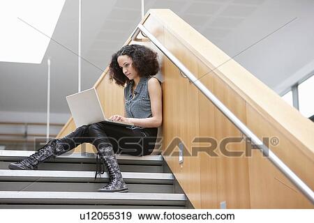 Businesswoman using laptop on office stairway View Large Photo Image Stock Photo - Businesswoman using laptop on office stairway. Fotosearch