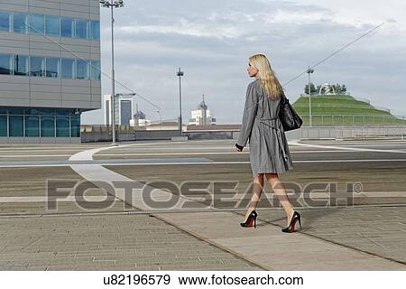 Stock Photo - "Businesswoman, walking outdoors along pathway, rear view". Fotosearch