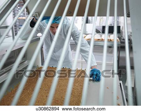 Picture - Cake product in cutting machine in cake factory. Fotosearch