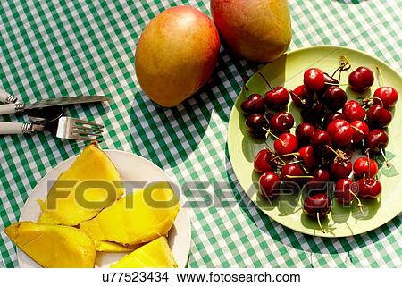 Picture - "Cherries and mangos on table, overhead view". Fotosearch
